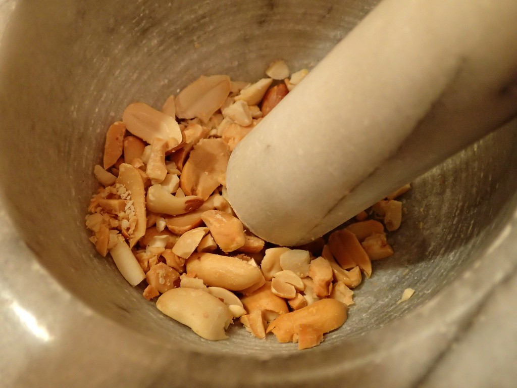 Crush peanuts in mortar and pestle